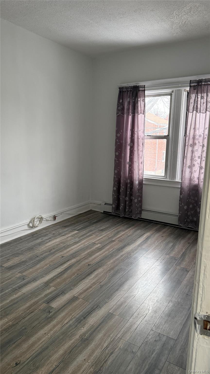 88-10 78th Street Queens, NY 11421 - Photo 16 of 19 an empty room with wooden floor and windows