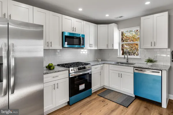 a kitchen with cabinets stainless steel appliances and wooden floor