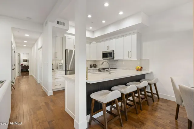 a living room with stainless steel appliances furniture a dining table and kitchen view