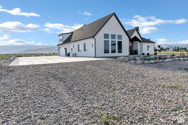 1952 Highway 118 Monroe, UT 84754 - Photo 5 of 88 Back of house with a mountain view, concrete driveway, a shingled roof, a garage, and stucco siding