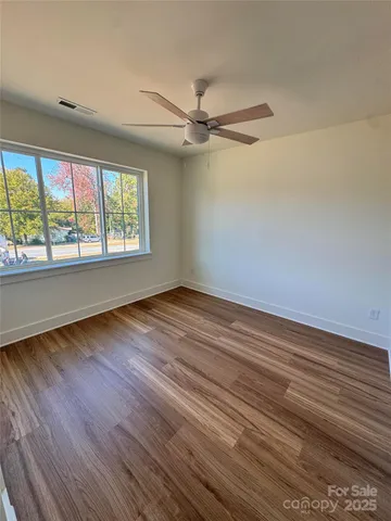 an empty room with wooden floor fan and windows