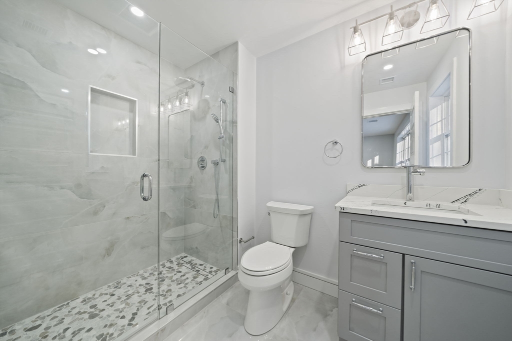 293 Cross Street Norwell, MA 02061 - Photo 26 of 42 a bathroom with a toilet a sink a glass door a shower and a mirror