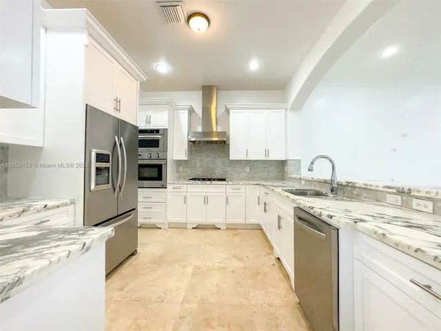 a large kitchen with stainless steel appliances granite countertop a stove a sink and a refrigerator