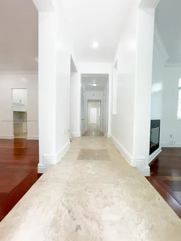a view of a hallway with wooden floor and a living room