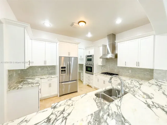 a kitchen with granite countertop a sink stove and refrigerator