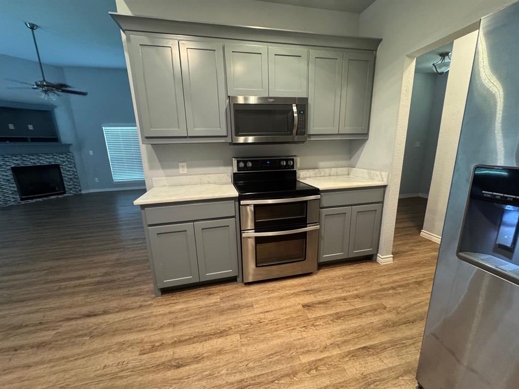 792 East Northside Drive Pilot Point, TX 76258 - Photo 6 of 18 a kitchen with granite countertop a stove and a microwave