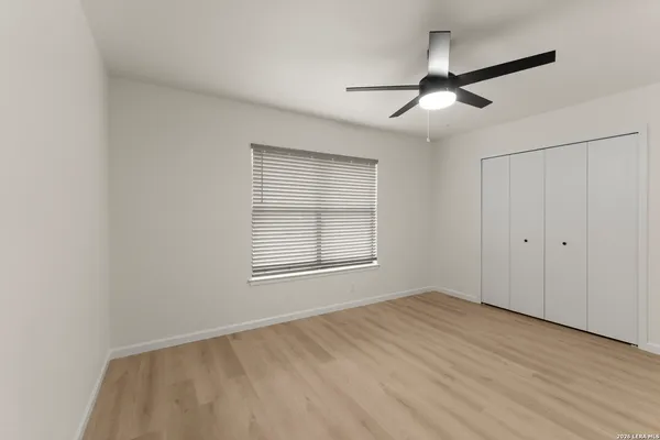 an empty room with wooden floor ceiling fan and windows