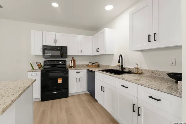 a kitchen with granite countertop a sink and white cabinets