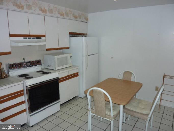 2903 Fallstaff Road, Unit 503 Baltimore, MD 21209 - Photo 11 of 20 a kitchen with stainless steel appliances granite countertop a table chairs stove and white cabinets