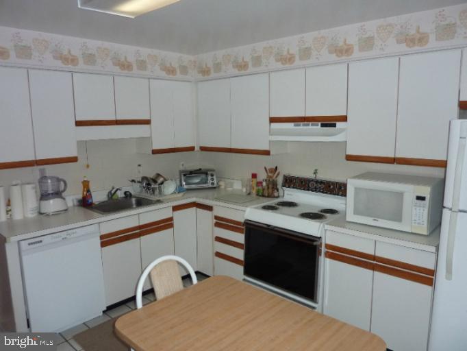 2903 Fallstaff Road, Unit 503 Baltimore, MD 21209 - Photo 9 of 20 a kitchen with stainless steel appliances granite countertop a sink dishwasher a stove and white cabinets with wooden floor