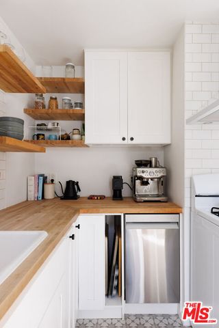 a kitchen with stainless steel appliances granite countertop a refrigerator a sink and white cabinets