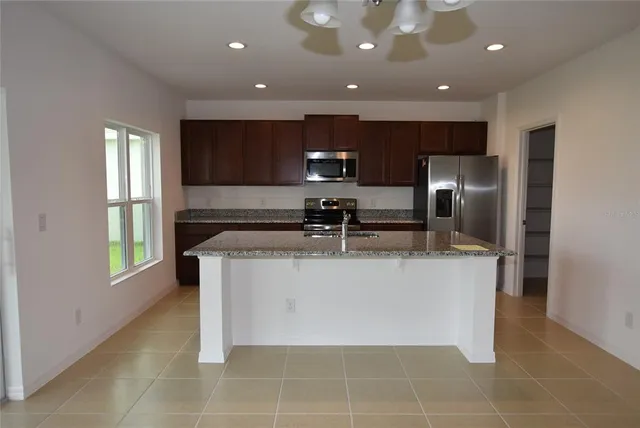 a view of kitchen with stainless steel appliances granite countertop a refrigerator a sink a oven and a cabinets