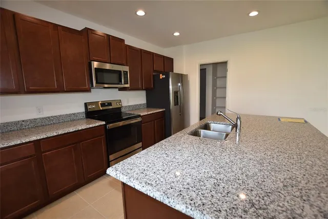 a kitchen with stainless steel appliances granite countertop a sink stove and refrigerator