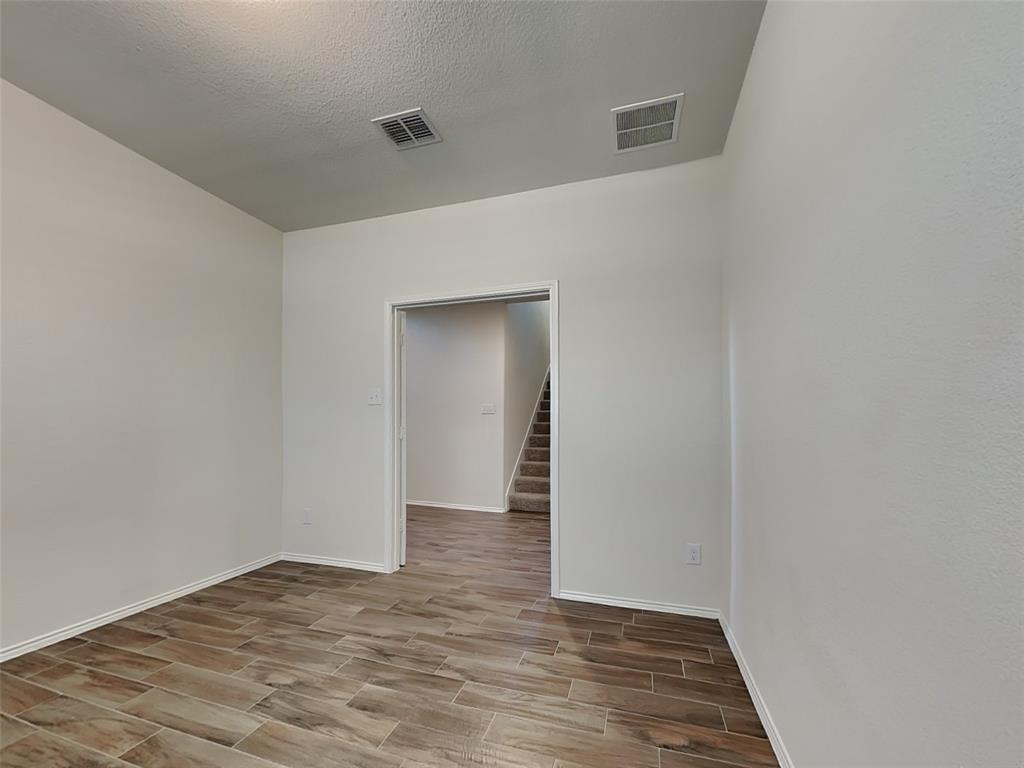 506 Robinson Way Fate, TX 75189 - Photo 8 of 30 Unfurnished room featuring wood tiled floors, stairway, and a textured ceiling