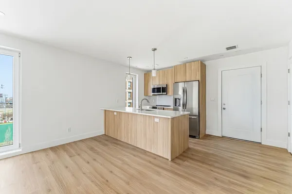 a kitchen with cabinets wooden floor and stainless steel appliances