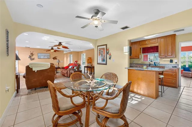 a dining hall with stainless steel appliances kitchen island granite countertop a dining table chairs and a refrigerator