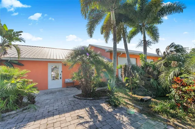 a view of a house with a yard and palm trees