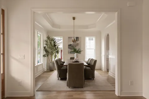 a living room with couches and kitchen view with wooden floor