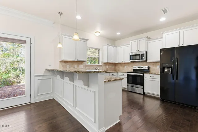 a kitchen with granite countertop a sink cabinets and wooden floor