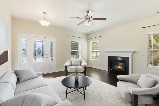 a view of an empty room with wooden floor fireplace and a window