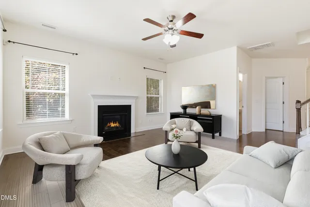 an empty room with windows a fireplace a ceiling fan and wooden floor
