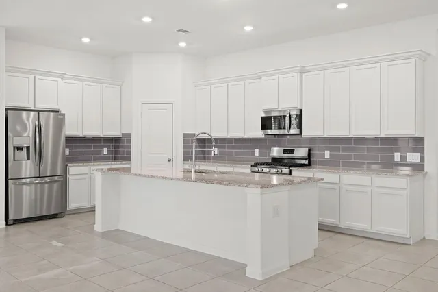 a kitchen with stainless steel appliances granite countertop a refrigerator a sink and white cabinets