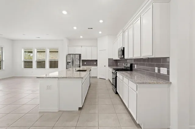 a kitchen with granite countertop white cabinets and stainless steel appliances