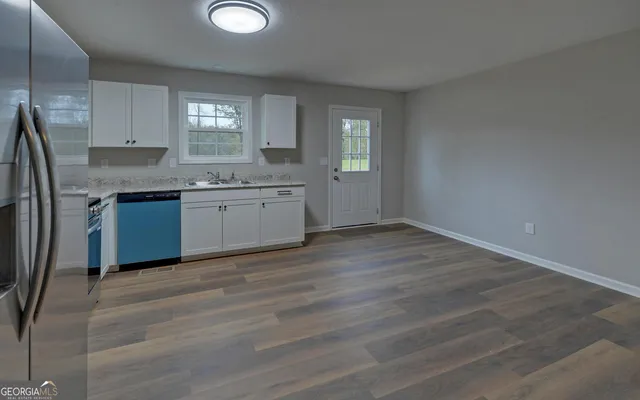 a kitchen with granite countertop a sink cabinets and wooden floor