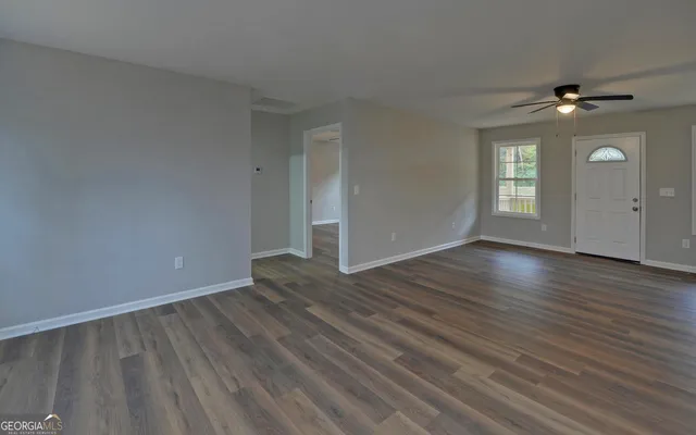 an empty room with wooden floor and windows