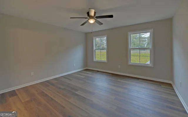 an empty room with wooden floor and windows
