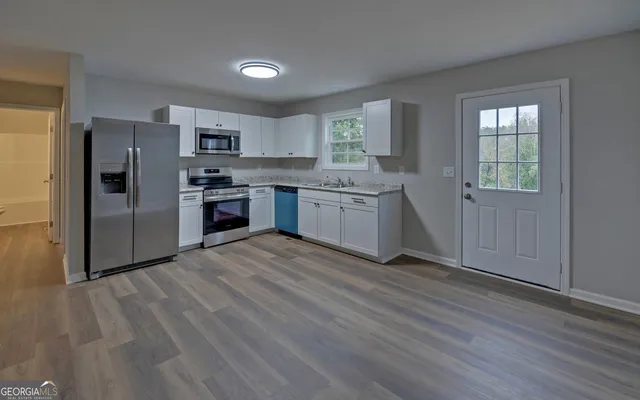 a kitchen with stainless steel appliances granite countertop a stove a sink dishwasher a refrigerator and a stove with wooden floors