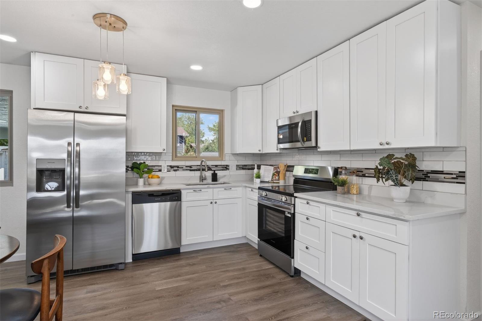 9079 Dudley Street Westminster, CO 80021 - Photo 7 of 37 a kitchen with white cabinets and stainless steel appliances