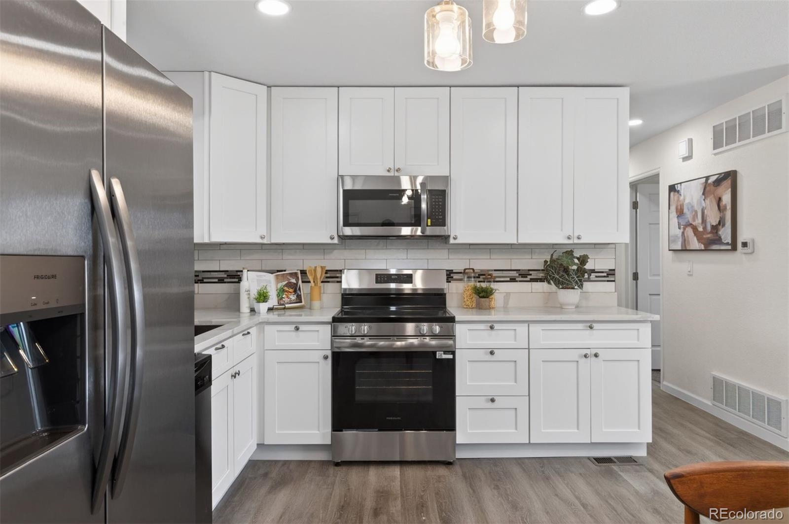 9079 Dudley Street Westminster, CO 80021 - Photo 9 of 37 a kitchen with cabinets stainless steel appliances and wooden floor