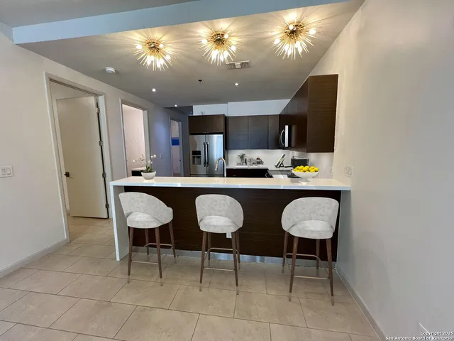 a kitchen with a dining table chairs and refrigerator