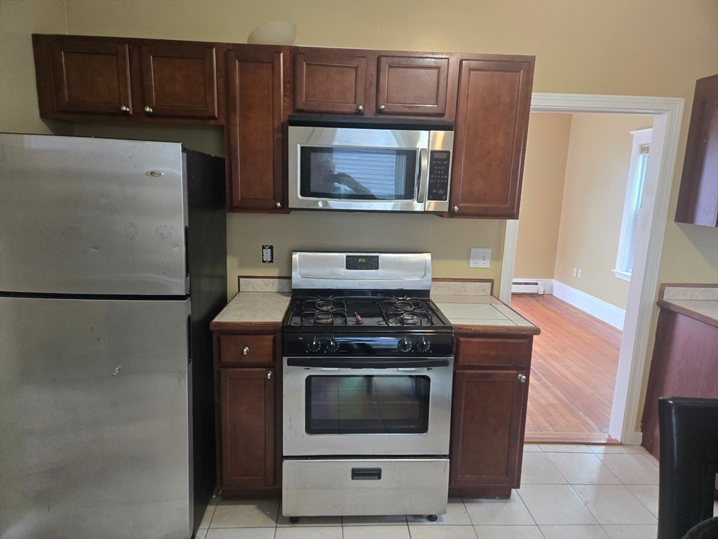 53 Groveland Street Lynn, MA 01902 - Photo 13 of 28 a kitchen with granite countertop a stove and a microwave with cabinets
