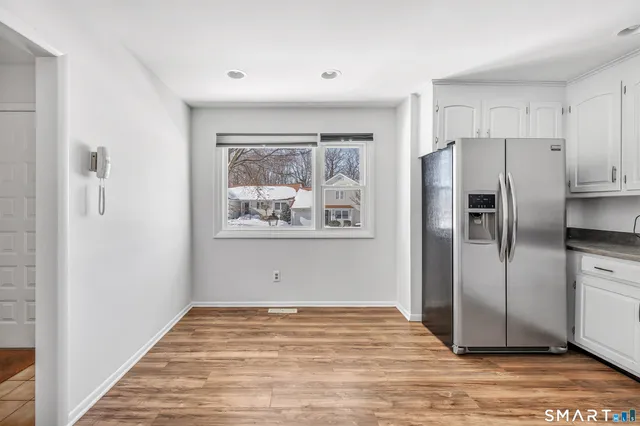 a view of a kitchen with wooden floor refrigerator and window