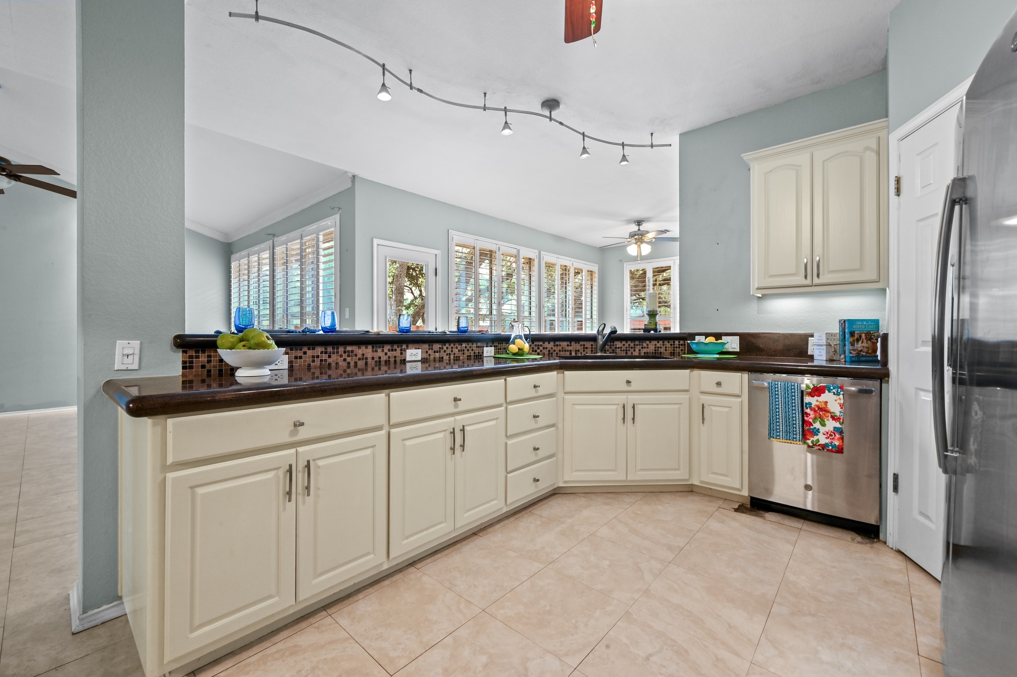 5313 Moon Shadow Drive Austin, TX 78735 - Photo 18 of 30 Kitchen featuring cream-colored cabinetry, a dark countertop, mosaic tile backsplash, stainless steel appliances, and track lighting