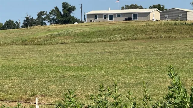 a view of a big house with a big yard and large trees