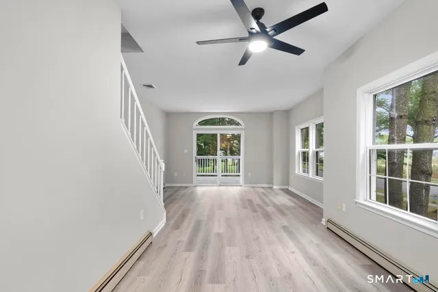 a view of an empty room with a window and wooden floor