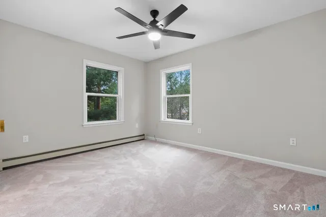 an empty room with windows and fan