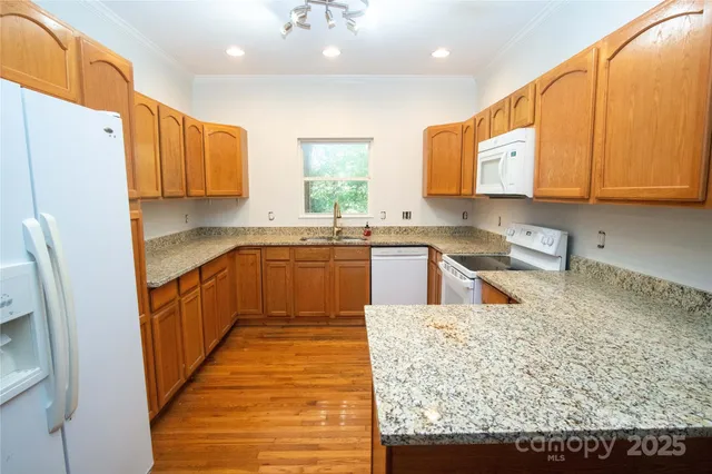 a kitchen with stainless steel appliances granite countertop a sink stove refrigerator and cabinets