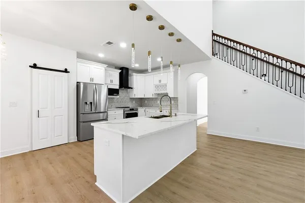 a large white kitchen with lots of white cabinets appliances and a wooden floor