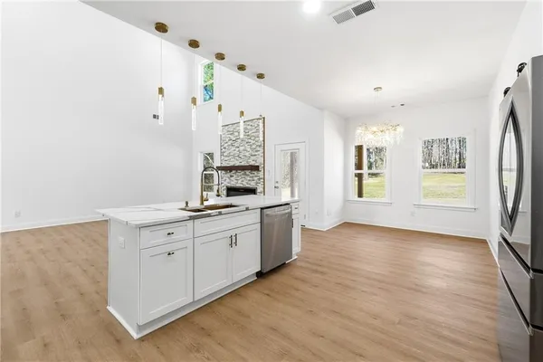 a kitchen with granite countertop a stove a sink and white cabinets with wooden floor