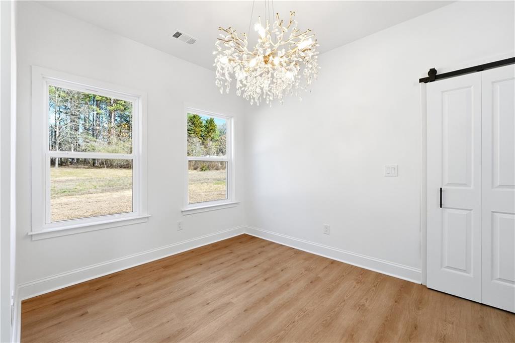 644 Hampton Road Hampton, GA 30228 - Photo 19 of 40 an empty room with wooden floor chandelier and windows