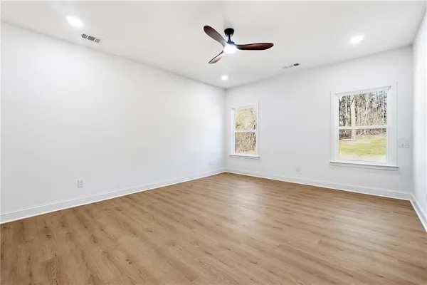 an empty room with wooden floor and windows