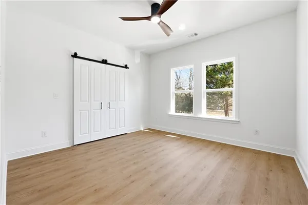 an empty room with wooden floor chandelier fan and windows