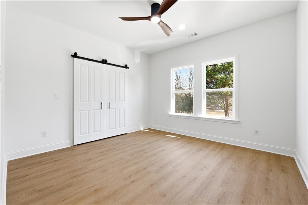 644 Hampton Road Hampton, GA 30228 - Photo 35 of 40 an empty room with wooden floor chandelier fan and windows