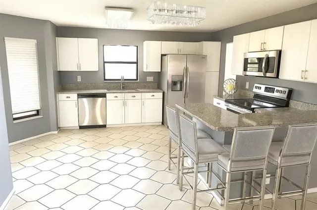 a kitchen with stainless steel appliances granite countertop a refrigerator and a stove top oven