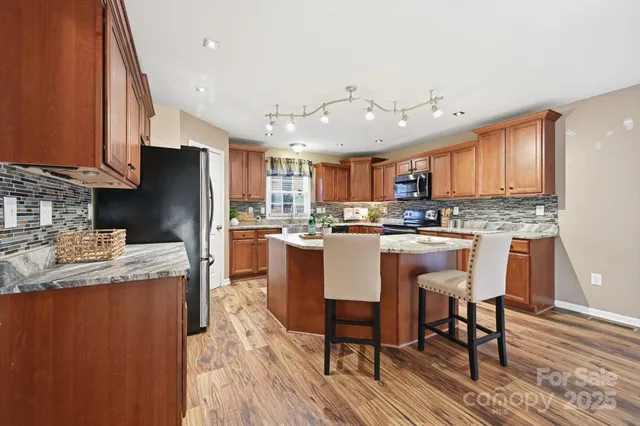 a kitchen with stainless steel appliances granite countertop a refrigerator a stove top oven a sink and dishwasher