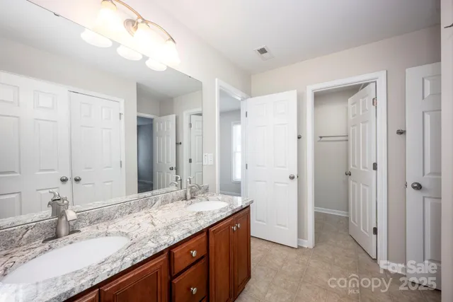a bathroom with a granite countertop double vanity sink and mirror
